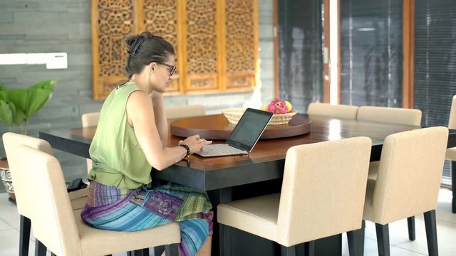 Woman sitting in the dining room and using notebook, steadycam shot
