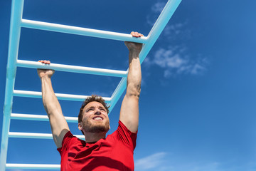 Fitness monkey bars man training arms muscles on jungle gym outdoors in summer. Athlete working out...