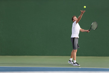 Tennis serve player man serving ball during match point on outdoor green court. Athlete playing...