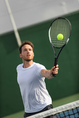 Tennis player man hitting volley with forehand returning ball playing on court. Athlete portrait training on summer practice. © Maridav