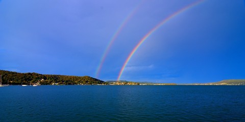 Spectacular vivid Double Rainbow photo in blue sky.
