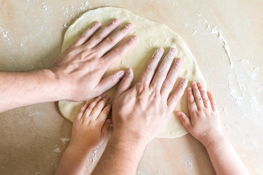 Children's and dad's hands on dough