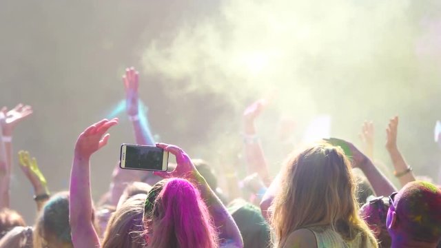 Holi Color Festival. Girl takes video on the smartphone. Slow motion 