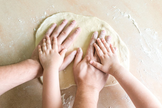 Children's and dad's hands on dough