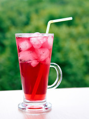 A glass of fruit juice with ice outdoors