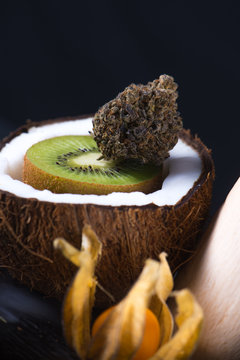 Detail of cannabis buds with fresh coconut and kiwi over black