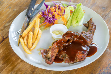 Steak with french fried on white dish on wooden table