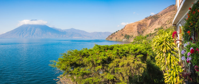 Scenic Panoramic View of Lake Atitlan and Volcano San Pedro in Guatemala from a secluded resort with luxuriant tropical vegetation.