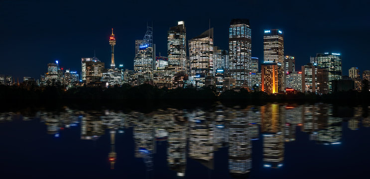 Mesmerizing Waterfront Skyline of Sydney's Central Business District with major modern skyscraper landmarks of Sydney and the City Tower at blue hour with reflections in the bay