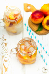 Homemade iced lemonade with ripe peaches. Fresh peach ice tea in a mason jar. Top view.