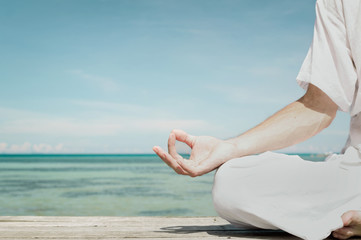 Man meditating in the lotus position on the beach close up