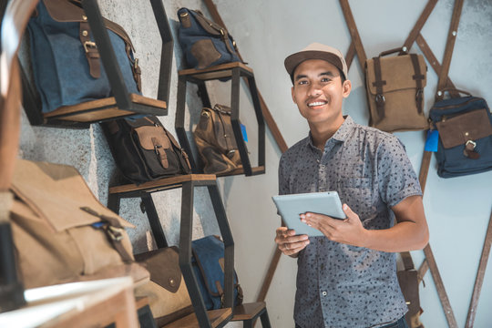 Asian Male Business Owner In A Bag Shop With Tablet