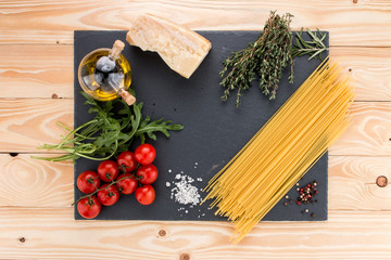 italian spaghetti, cherry tomatoes, olive oil, thyme, parmesan, arugula on black slate tray, top view, italian food concept - 167876534
