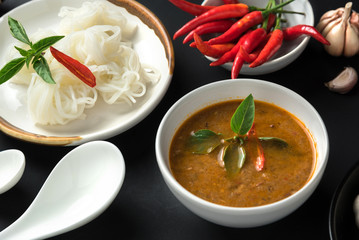 Noodle and fish curry sauce with ingredient on black table.