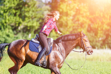 Happy young woman riding galloping horse at sunny summer day. Freedom equestrian concept image