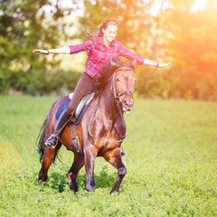 Happy young woman riding galloping horse at sunny summer day. Freedom equestrian concept image