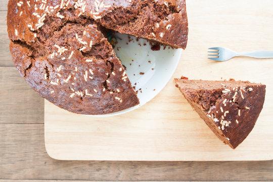 Overhead view of banana chocolate cake with a cut piece on wooden plate