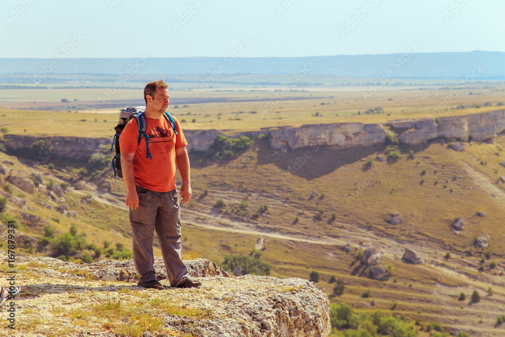 Wall mural tourist with a backpack on top of the mountain.