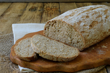 A loaf of homemade bread from whole grain  and rye flour whith sesame seeds on a wooden background. Copy space. Photographing with natural light