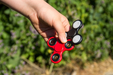 Boy playing with two fidget spinner stress relieving toys outdoor