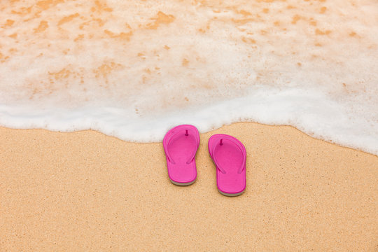 Pair of slippers on white sand beach. 