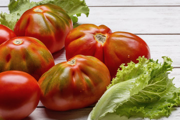 Red tomatoes and salad on white wooden board