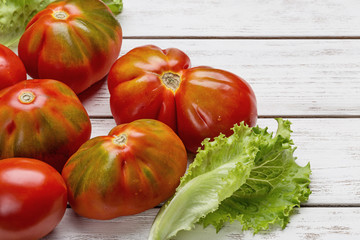 Red tomatoes and salad on white wooden board