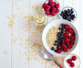 homemade oatmeal with berries for breakfast on white wooden board
