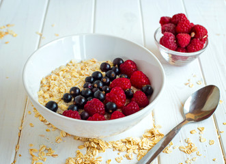 homemade oatmeal with berries for breakfast on white wooden board