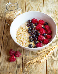 homemade oatmeal with berries for breakfast on white wooden board