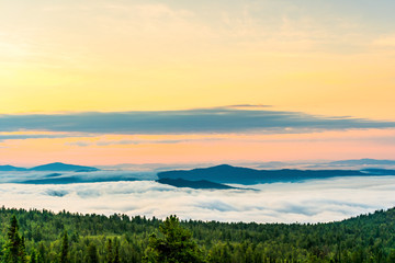 Breathtaking sunrise and mist over the tops of mountains and woods
