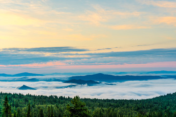 Breathtaking sunrise and mist over the tops of mountains and woods
