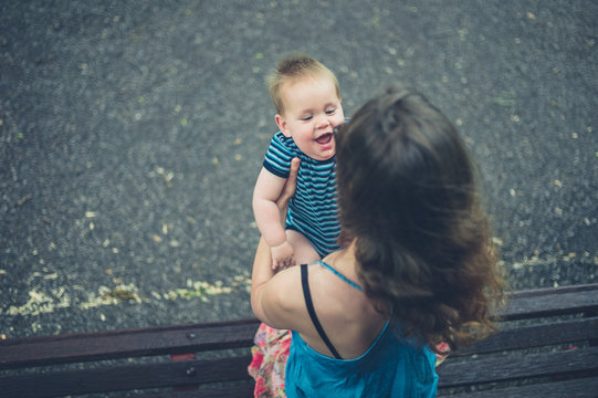Mother with laughing baby on park bench