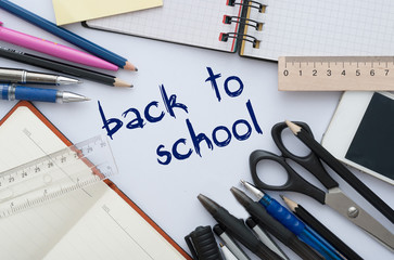 School set with back to school inscription in notebook and stationery on wooden background