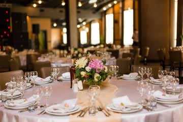 Beautiful table setting with crockery and flowers for a party, wedding reception or other festive event. Glassware and cutlery for catered event dinner.