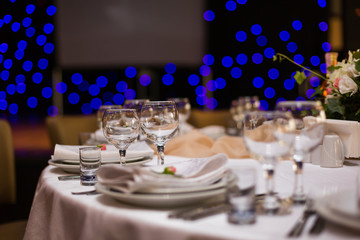 Beautiful table setting with crockery and flowers for a party, wedding reception or other festive event. Glassware and cutlery for catered event dinner.