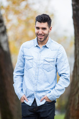 Handsome happy man in the park. Autumn scenery