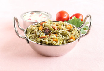 Homemade rice pilaf, a popular and traditional Indian food, made from rice and vegetables like carrot, capsicum and peas, and yogurt tomato salad.