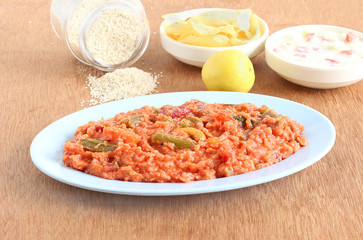 Homemade healthy Indian food pilaf made from brown top millet and lentil in a plate with yogurt salad and potato chips as side dishes.