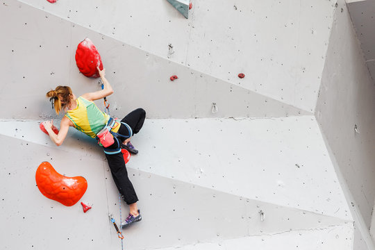Sporty young woman exercising in a colorful climbing gym