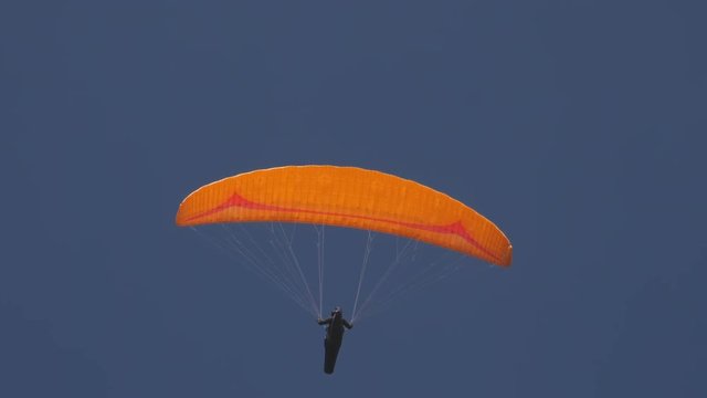 The paraglider on the yellow wing flies over the camera, slow motion