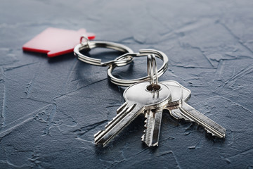 estate concept with key, red keychain with house symbol, concrete