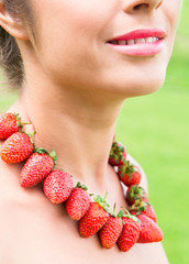 beautiful woman neck with red beads made of fresh strawberry