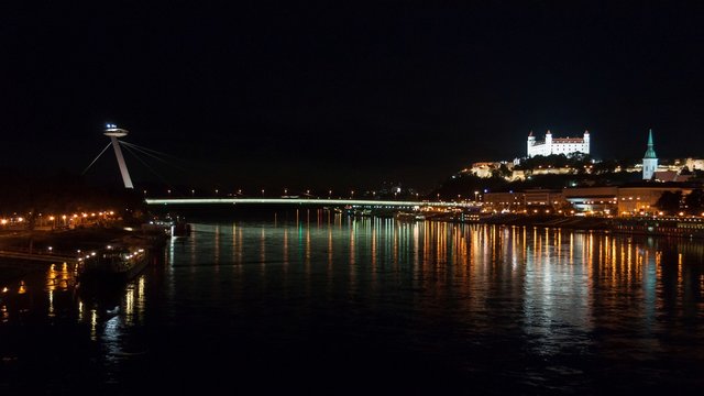 Night view of the lighted SNP bridge over Danube river and castle in capital city Bratislava, Slovakia