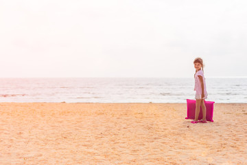 Little girl on the beach with a bag, kids travel