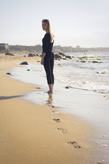 sad blond barefoot woman looking back at sunny sea beach