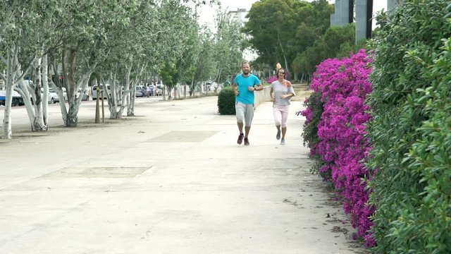Young couple jogging in city park, super slow motion 120fps
