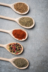 Fresh herbs and spices on wooden spoons.
