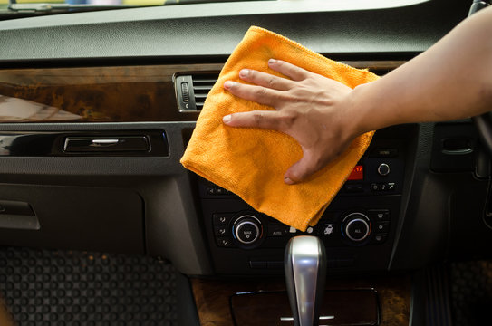 Hand with microfiber cloth cleaning interior car
