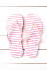 Pink flip flops on white wooden background